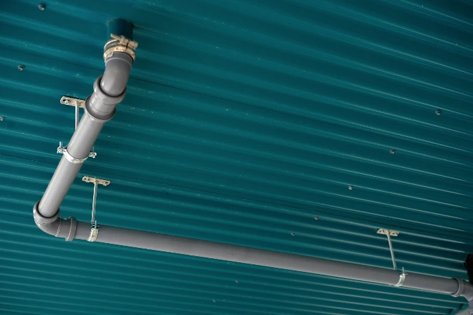 Pipes are installed on a teal, ribbed ceiling.